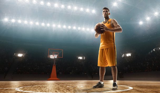 Ammattimainen koripalloilija, jolla on pallo tyhjällä valonheitinkentällä vanteella
 - Valokuva, kuva