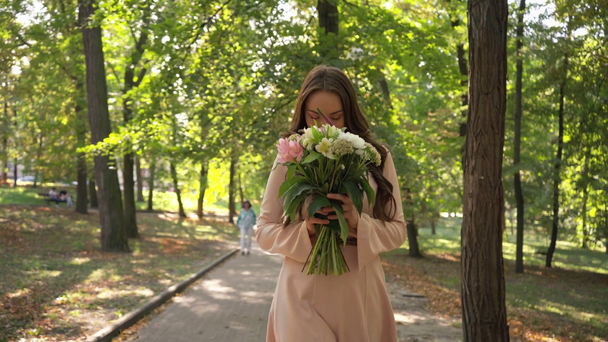 όμορφη νεαρή γυναίκα με μπουκέτο περπάτημα στο πάρκο - Πλάνα, βίντεο