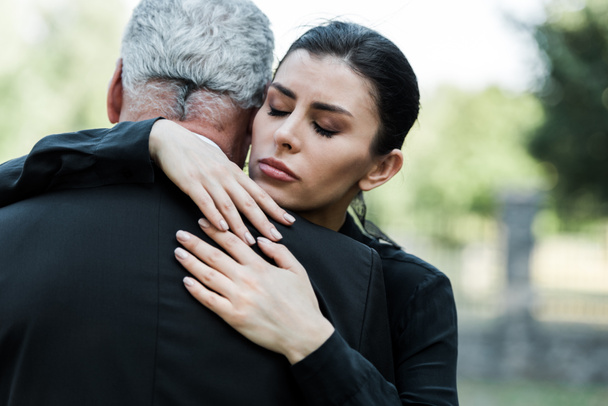 расстроенная женщина с закрытыми глазами обнимает старшего мужчину
 - Фото, изображение