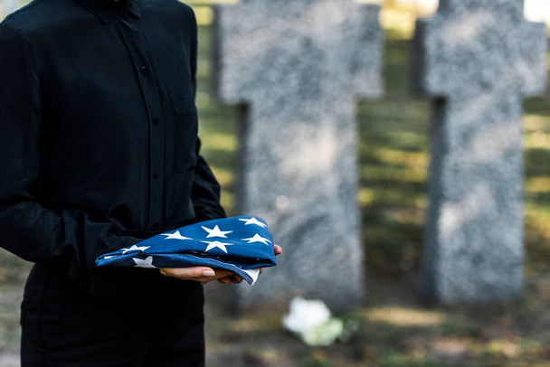recortado vista de la mujer sosteniendo bandera americana en el cementerio
  - Foto, Imagen