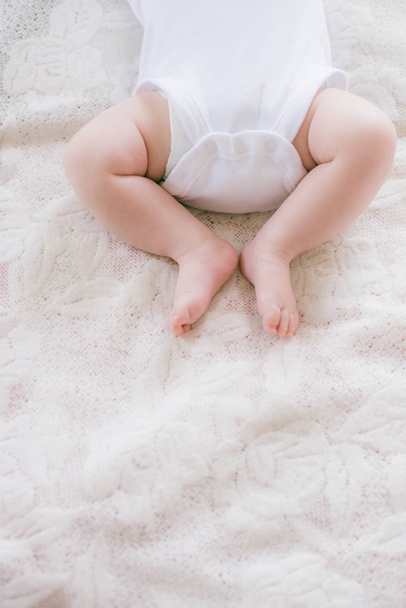 Little legs of a baby lying on a white bed at home. Happy motherhood. - Foto, Imagem