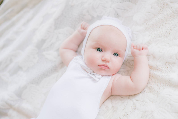 Niedliche Kleinkind Baby in weißen Kleidern liegt auf einem weißen Bett zu Hause - Foto, Bild
