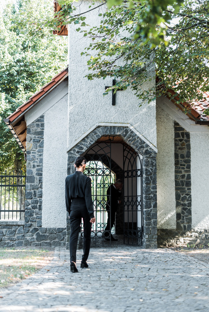 back view of woman walking into church near trees  - Photo, Image