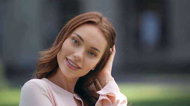 young woman touching hair and looking at camera - Кадри, відео