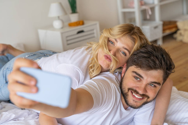 Sweet couple is making selfie in bedroom - 写真・画像