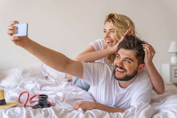 Smiling couple in love making selfie in bed - Photo, image