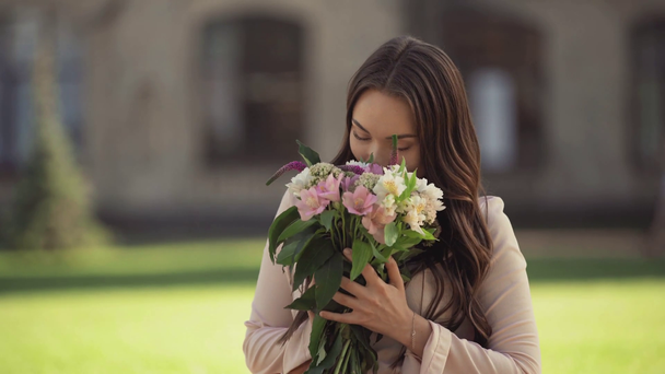 young woman sitting on grass and getting flowers - Záběry, video