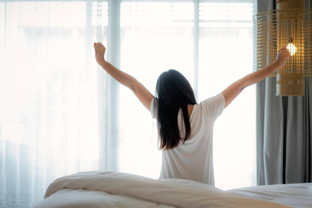 Rückseite der asiatischen Frau streckt Hände und Körper im Bett nach  - Foto, Bild