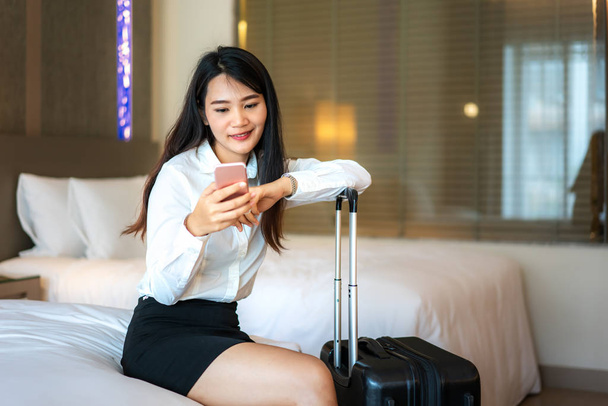 Asian woman reading phone messages in hotel room. Female executi - Photo, image