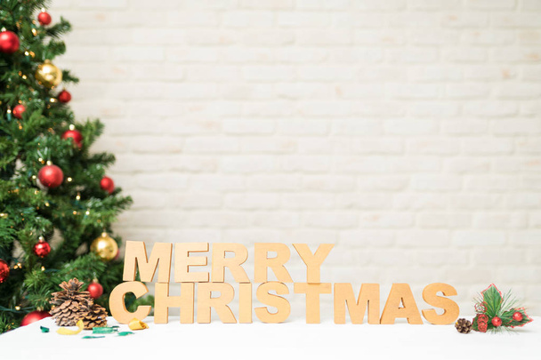 Dřevěná písmena tvořící "Veselé Vánoce" se spoustou místa na kopírování a vedle stromu se světly - Fotografie, Obrázek