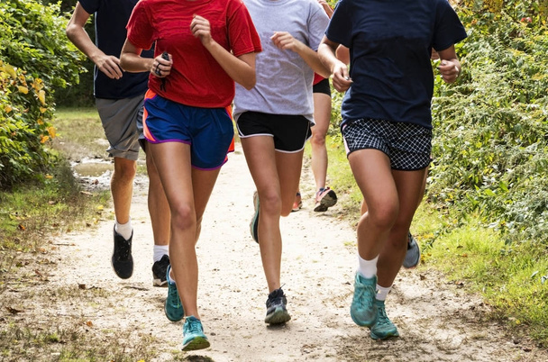 Front view of a group of runners training on a dirt path in the  - Photo, Image