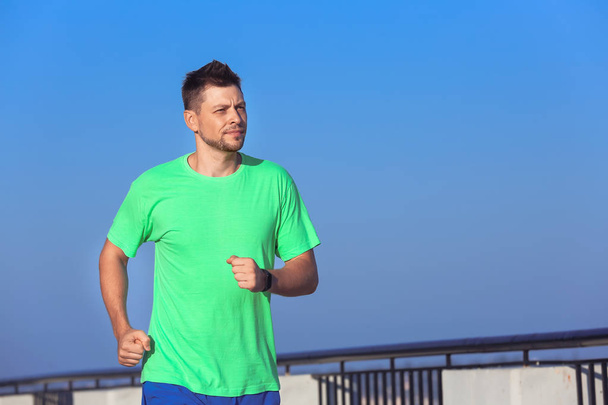 Handsome sporty man running outdoors - Foto, afbeelding