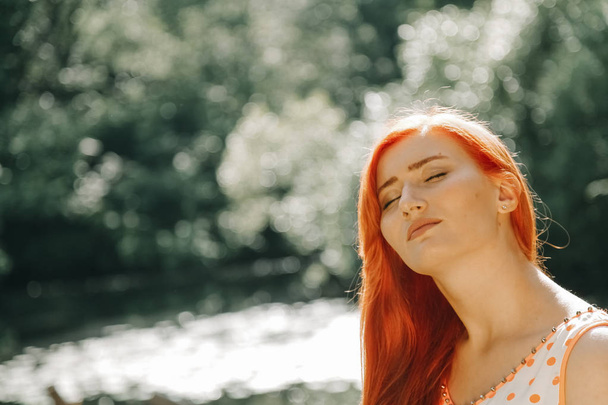 cute redheaded girl walking in the summer hot city park - Valokuva, kuva