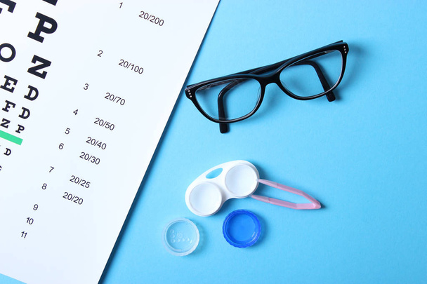 стол для проверки зрения, очки и линзы для коррекции зрения на цветном фоне, вид сверху. Аксесуары для офтальмолога. - Фото, изображение