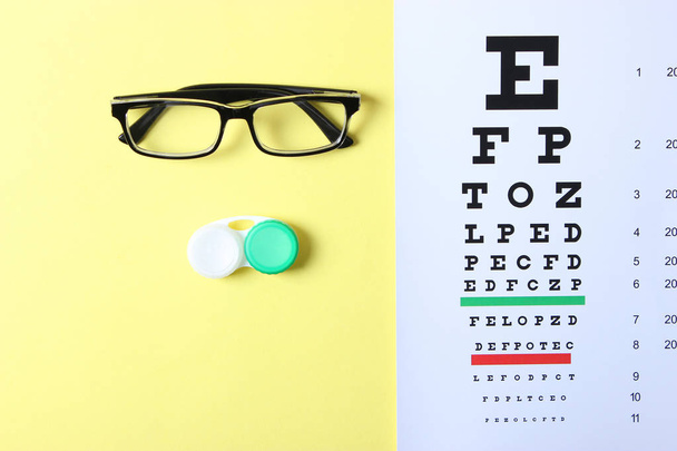 une table pour vérifier la vision, des lunettes et des lentilles pour corriger la vision sur un fond coloré, vue de dessus. Ophtalmologiste Accessoires. - Photo, image