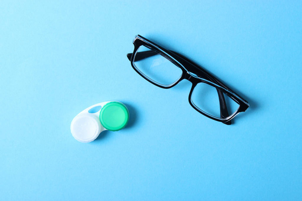 ein Tisch zur Überprüfung des Sehvermögens, Brillen und Gläser zur Korrektur des Sehvermögens auf farbigem Hintergrund, Draufsicht. Augenarzt Zubehör. - Foto, Bild