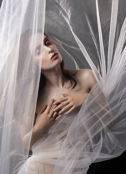 A beautiful slim topless girl poses among the white fabric of a  - Фото, зображення