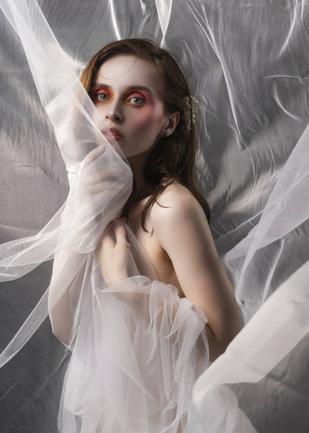 A beautiful slim topless girl poses among the white fabric of a  - Φωτογραφία, εικόνα