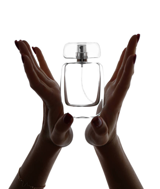 Silhouet van de vrouwelijke handen met een fles parfum op witte achtergrond - Foto, afbeelding