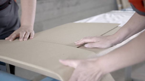 Close-up of workers packed flat package. Action. Workers in overalls pack building material from factory for home delivery. Building materials or furniture are delivered directly from factory - Valokuva, kuva