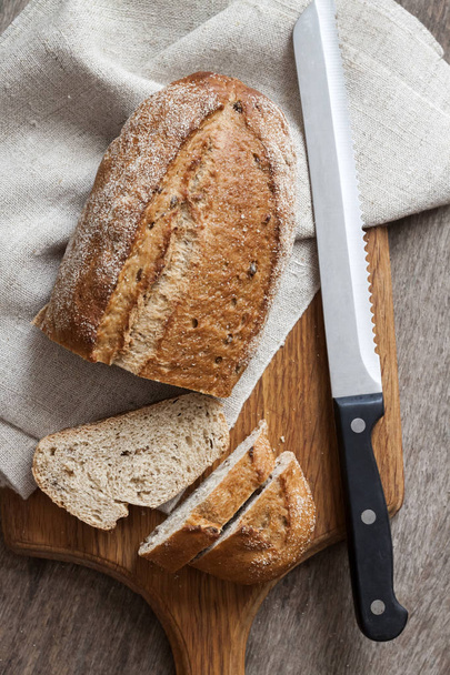 Vekni teljes kiőrlésű kenyér, szeletekkel, fa fedélzeten konyhaasztalon - Fotó, kép
