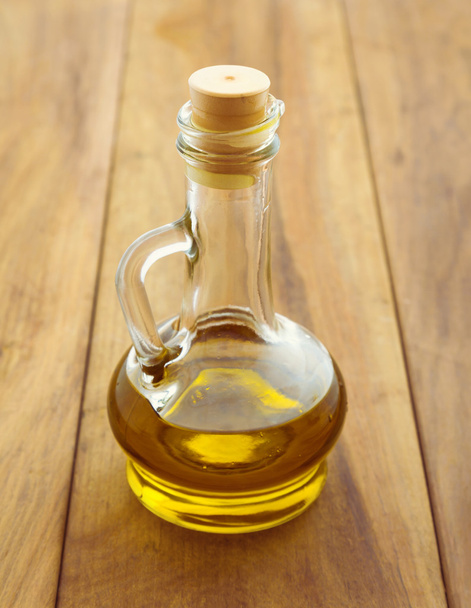 Olive oil in bottle over wooden background - Фото, изображение