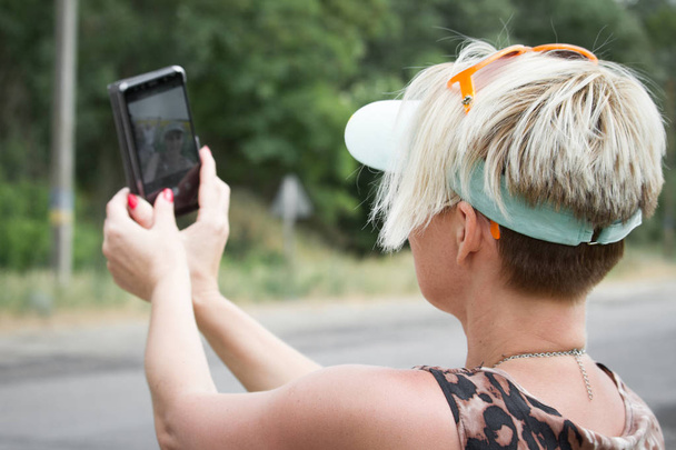 Femme blonde adulte fait selfie sur un smartphone sur un fond de champ de tournesols, mise au point sélective
 - Photo, image