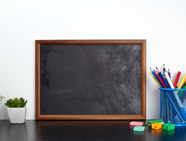 empty black chalk board, multi-colored pencils in a blue metal s - Photo, Image