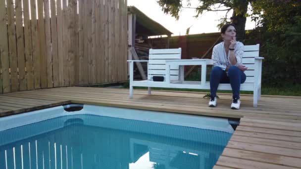 Lány cigaretta füst a medence. Este pihenő a medencénél - Felvétel, videó