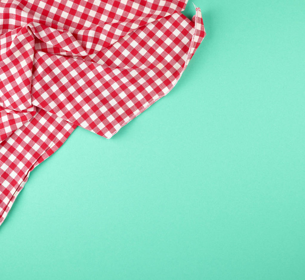 toalla de cocina a cuadros rojo blanco sobre un fondo verde
 - Foto, Imagen