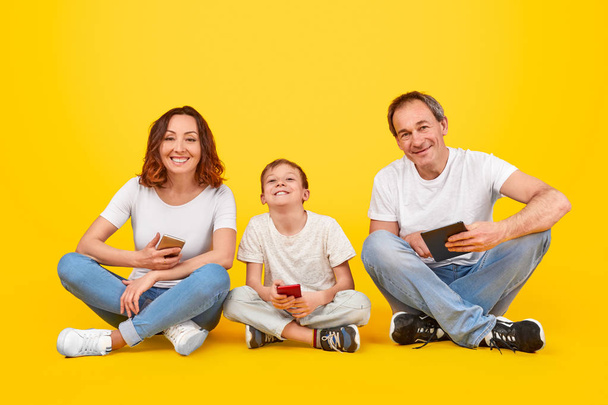 Cheerful family with digital devices - Zdjęcie, obraz