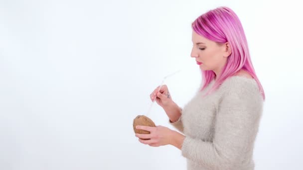 Молодая женщина кладет соломинку в кокос и начинает пить из него.
. - Кадры, видео