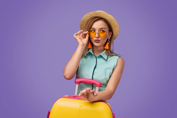 Trendy young traveler with suitcase pouting lips - Foto, imagen