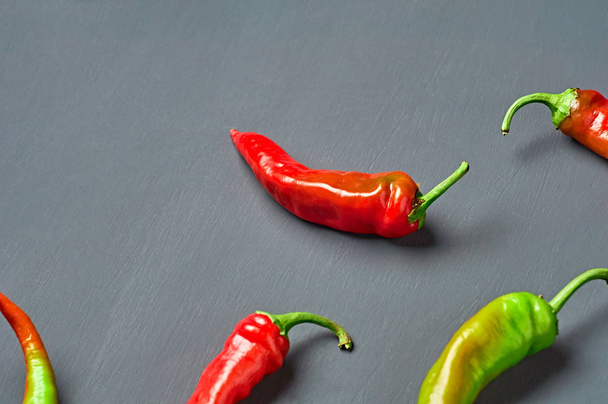 Many scattered whole red and green color hot chilli peppers on dark concrete background. Space for text - Foto, Bild