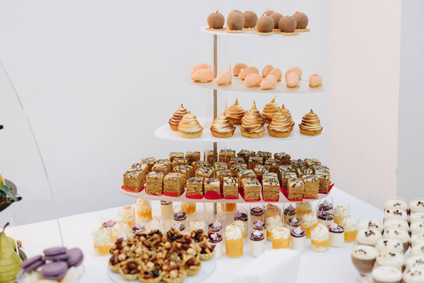ein Stand mit verschiedenen Desserts und Kuchen auf einem Banketttisch - Foto, Bild