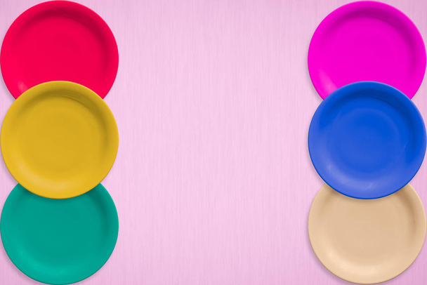 Χρωματιστά κεραμικά στρογγυλά πιάτα πάνω σε ροζ φόντο - Φωτογραφία, εικόνα