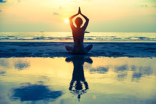 Yoga vrouw in lotus pose zittend op het strand - Foto, afbeelding