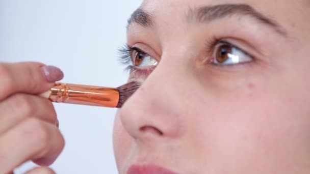 Make-up umělec dává trochu kondenzátoru pod oči klienta. Nejprve aplikuje základ a pak přejde na nanášení očních stínů a červeného prášku. - Záběry, video
