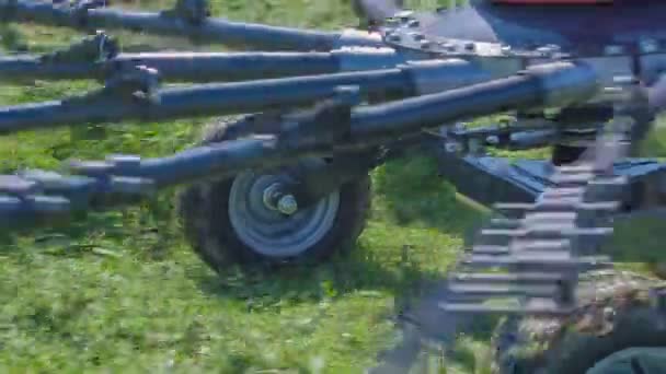 Roterende harken bewegen snel wanneer een tractor op het grote grasveld rijdt. - Video