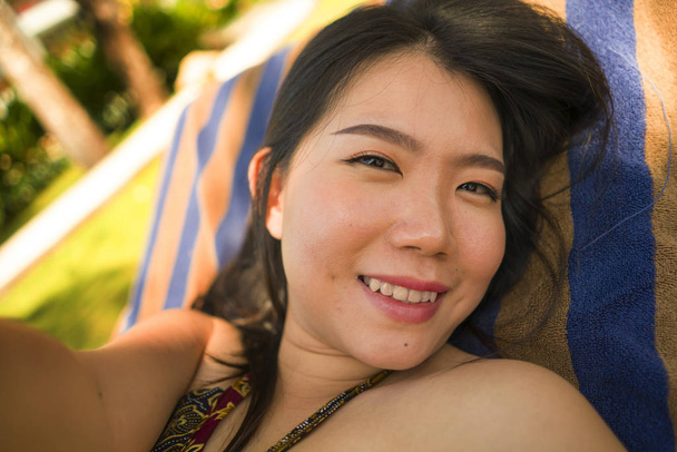 young beautiful and happy tourist Asian Korean woman taking selfie at tropical resort pool hammock smiling carefree and natural in Summer holidays getaway  - Foto, afbeelding