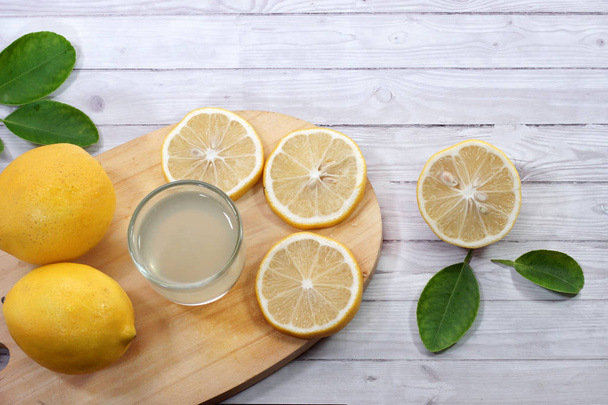 fresh lemon juice  on a glass and lemon slices served on cutting board - Photo, Image