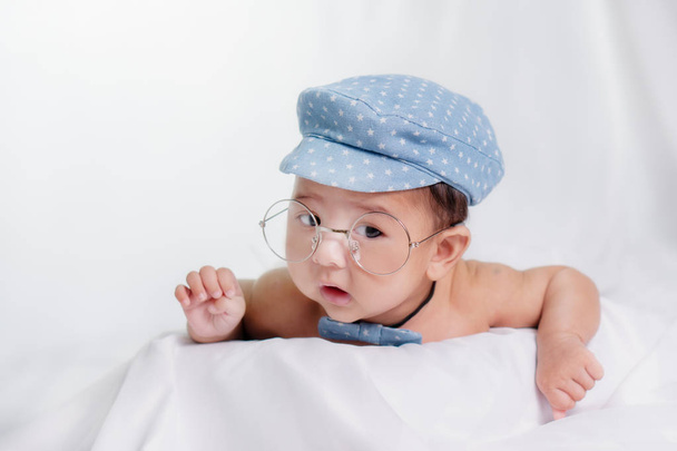 portrait of asian infant baby boy with blue cap and glasses on w - Zdjęcie, obraz