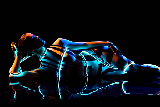 Naked girl lying in water and leds the dark - Foto, Imagen