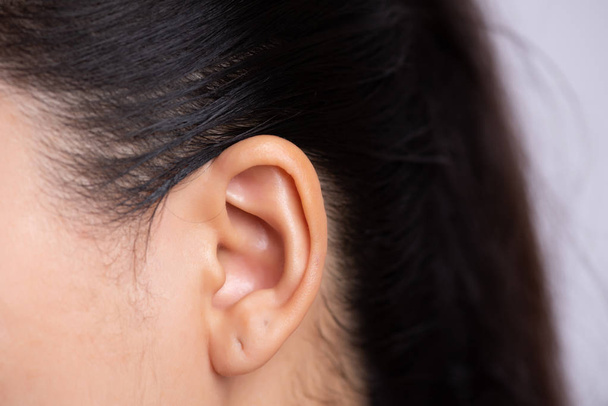 耳ピアスで若いアジアの女性の耳をクローズアップ。ヘルスケアと耳のクリーニングの概念. - 写真・画像