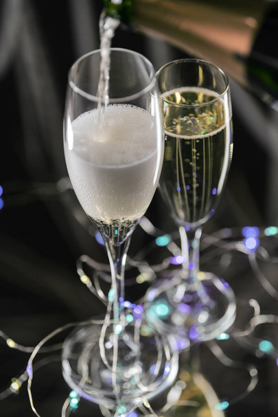 Κάθετη εικόνα από δύο γυάλινα ποτήρια με μια πολυτελή και αφρώδη σαμπάνια. Η ιδέα της γιορτής των Χριστουγέννων. Αεροφωτογραφία - Φωτογραφία, εικόνα