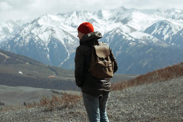 Guy piros Beanie állva a hegyek előtt - Fotó, kép