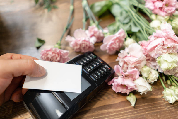 Concept contactless payment. Making payment with credit card and pos terminal, printed check. Floral shop concept . Flowers delivery - Zdjęcie, obraz