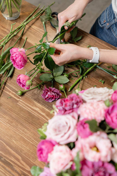 Nő virágárus létre virágkötészeti egy fonott kosárba. Gyönyörű csokor vegyes virágokkal. Floral Shop koncepció. Szép friss csokor. Virágok szállítása - Fotó, kép