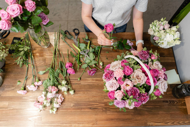 Woman florist create flower arrangement in a wicker basket. Beautiful bouquet of mixed flowers. Floral shop concept . Handsome fresh bouquet. Flowers delivery - Foto, imagen