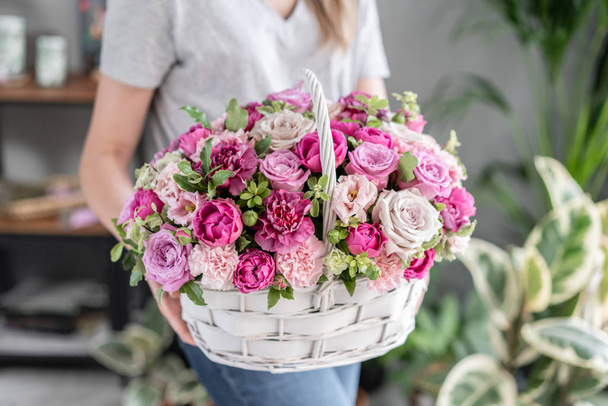 Flower arrangement in Wicker basket. Beautiful bouquet of mixed flowers in woman hand. Floral shop concept . Handsome fresh bouquet. Flowers delivery - Photo, Image